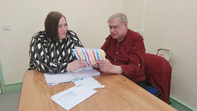 An advocate sitting with a service user, talking through paperwork together